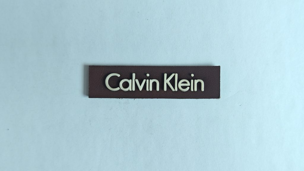 Apparel labels — elongated base with raised 3D text — actual product photo 1